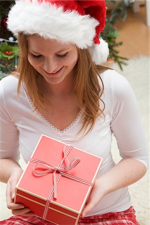 simsearch:659-03526649,k - Woman in Father Christmas hat looking at Christmas gift Stock Photo - Premium Royalty-Free, Code: 659-03525859