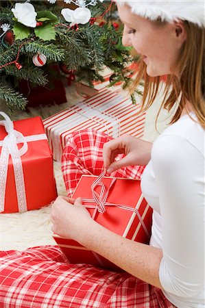simsearch:659-03526649,k - Woman in Father Christmas hat opening Christmas gift Stock Photo - Premium Royalty-Free, Code: 659-03525862