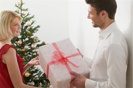 simsearch:659-03526649,k - Couple with Christmas gift in front of Christmas tree Stock Photo - Premium Royalty-Free, Code: 659-03526672