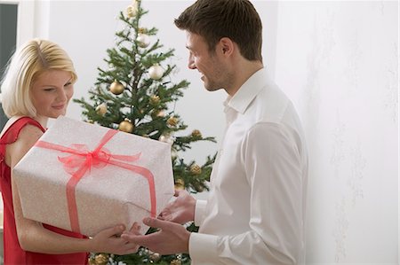 simsearch:659-03526649,k - Couple with Christmas gift in front of Christmas tree Stock Photo - Premium Royalty-Free, Code: 659-03526673