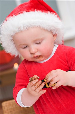 Baby in Father Christmas hat, messy with chocolate Stock Photo - Premium Royalty-Free, Code: 659-03526803