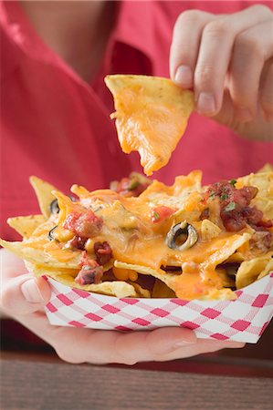 Woman holding nachos with melted cheese in cardboard container Stock Photo - Premium Royalty-Free, Code: 659-03527128