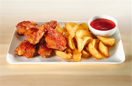 Chicken wings with potato wedges and ketchup Stock Photo - Premium Royalty-Free, Code: 659-03529704