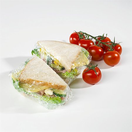 packed - Sandwiches in clingfilm, tomatoes beside them Foto de stock - Sin royalties Premium, Código: 659-03522258
