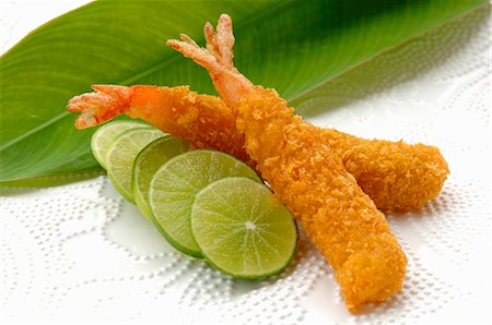 Breaded, deep-fried prawns with slices of lime Stock Photo - Premium Royalty-Free, Code: 659-03523847