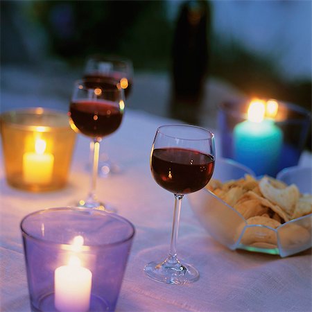 Glasses of red wine and crisps on candlelit table Stock Photo - Premium Royalty-Free, Code: 659-03534743
