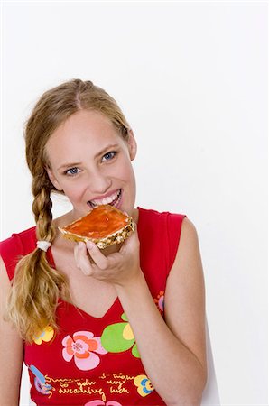 Woman biting into a slice of bread with jam Stock Photo - Premium Royalty-Free, Code: 659-03535506