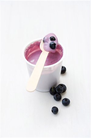 Blueberry yoghurt in plastic pot with wooden spoon Stock Photo - Premium Royalty-Free, Code: 659-03537244