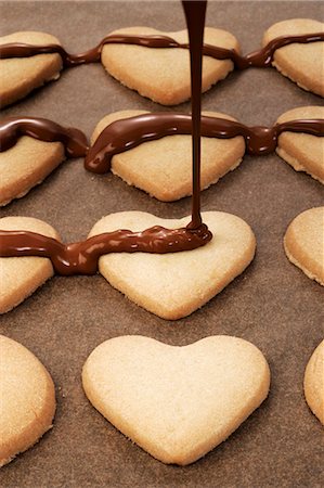 frosted - Decorating heart-shaped biscuits with couverture chocolate Stock Photo - Premium Royalty-Free, Code: 659-03530781
