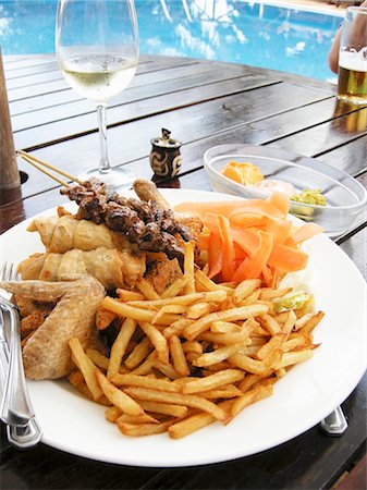 Plate of barbecued food and chips on table by swimming pool Stock Photo - Premium Royalty-Free, Code: 659-03533896