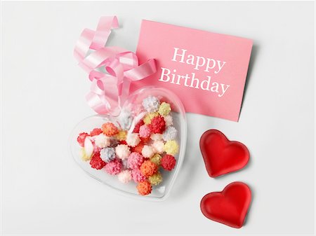 sugar - Transparent heart filled with multicolored sugar balls and a tag with the inscrition "Happy Birthday" Stock Photo - Premium Royalty-Free, Code: 652-05808838