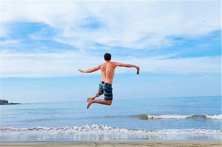 Man leaping in air on beach Stock Photo - Premium Royalty-Free, Code: 673-06964488