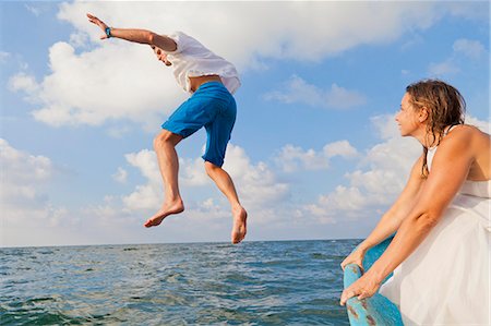 person jumping lake not dock - Woman watching man jump off boat Stock Photo - Premium Royalty-Free, Code: 673-06964480