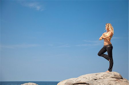 Young woman in yoga pose on rock by ocean Stock Photo - Premium Royalty-Free, Code: 673-06964664