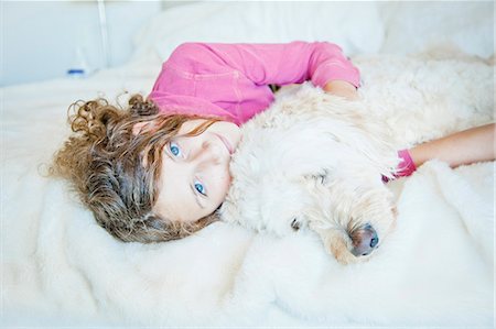 Teen girl cuddling dog on bed Stock Photo - Premium Royalty-Free, Code: 673-06964702