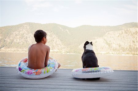 Young boy and dog wearing float rings on dock Stock Photo - Premium Royalty-Free, Code: 673-06964852