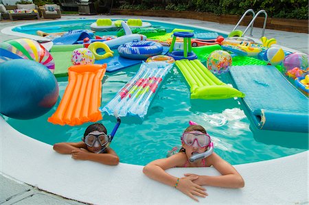 simsearch:400-05381058,k - Two children wearing scuba masks and snorkels swim in a pool full of inflatable toys Stock Photo - Premium Royalty-Free, Code: 673-08139186