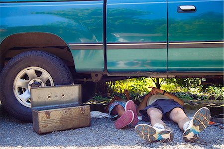 fixing - Man and a boy lying under a vehicle with a toolbox, doing repairs Stock Photo - Premium Royalty-Free, Code: 673-08139231