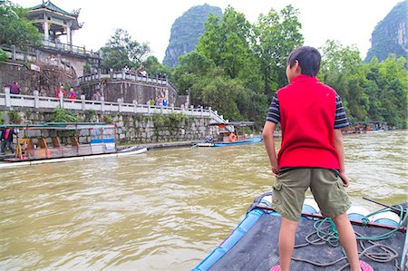 rail travel - Boy standing on a bamboo raft on the Li River, Yangshuo, China Stock Photo - Premium Royalty-Free, Code: 673-08139274