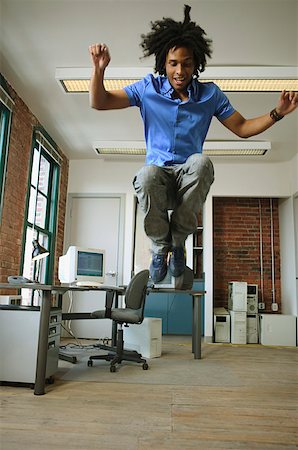 A young man leaping high in the air in a loft-style office. Stock Photo - Premium Royalty-Free, Code: 673-02137566