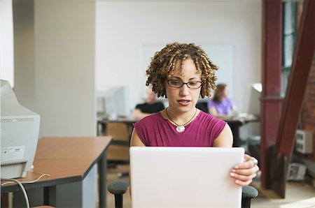Seated at her desk, a multi- ethnic woman, 20s, works at computer. Stock Photo - Premium Royalty-Free, Code: 673-02137588