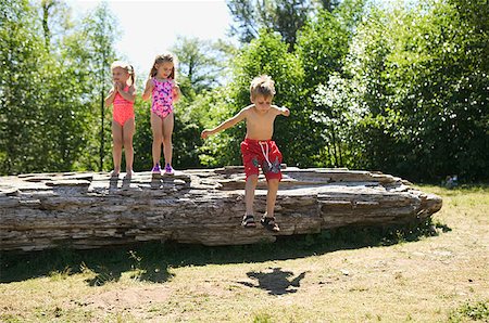 summer camping fire - Three young children playing on a fallen log. Stock Photo - Premium Royalty-Free, Code: 673-02137844