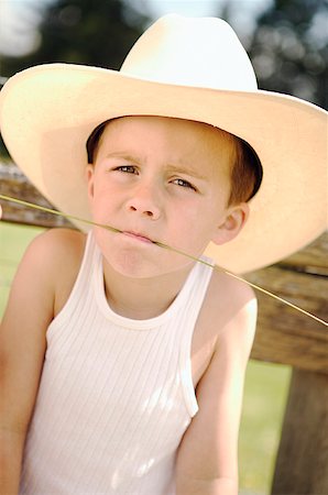 Boy wearing a cowboy hat and chewing on grass. Stock Photo - Premium Royalty-Free, Code: 673-02137946