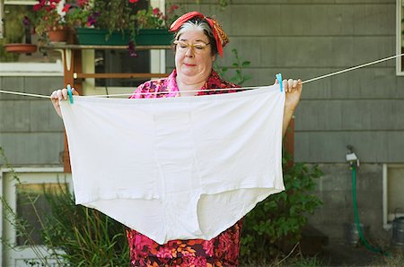 Woman hanging oversized underwear on a clothesline. Stock Photo - Premium Royalty-Free, Code: 673-02138554