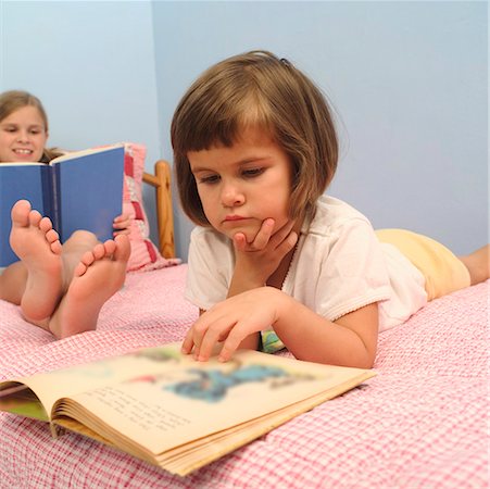 Young girls reading on a bed. Stock Photo - Premium Royalty-Free, Code: 673-02138579