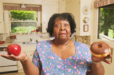 fat black woman - Woman deciding between an apple or a doughnut Stock Photo - Premium Royalty-Free, Code: 673-02138772