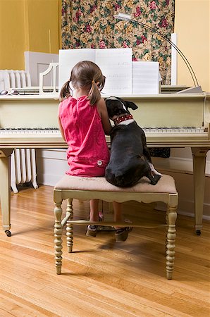 Girl and pet dog sitting on piano bench Stock Photo - Premium Royalty-Free, Code: 673-02139502