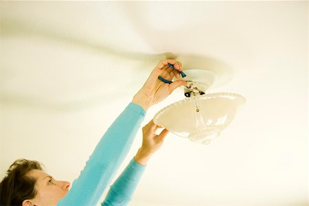 fixture - Woman repairing lighting fixture on ceiling Stock Photo - Premium Royalty-Free, Code: 673-02139905