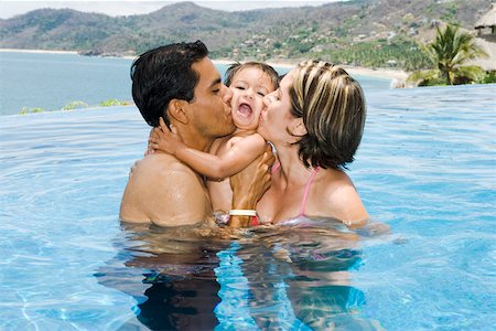 Parents kissing toddler in tropical pool Stock Photo - Premium Royalty-Free, Code: 673-02139969