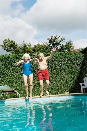 senior women swimming - Senior couple jumping into pool Stock Photo - Premium Royalty-Free, Code: 673-02140201