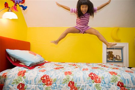 Young girl jumping on bed Stock Photo - Premium Royalty-Free, Code: 673-02140274