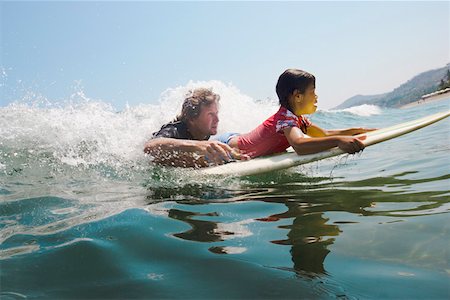 Father and daughter paddling surfboard Stock Photo - Premium Royalty-Free, Code: 673-02140739