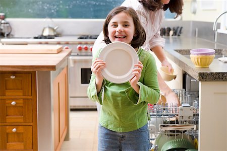 Laughing daughter unloading dishwasher with mother Stock Photo - Premium Royalty-Free, Code: 673-02140765