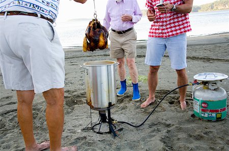 Men barbecuing chicken on beach Stock Photo - Premium Royalty-Free, Code: 673-02141474