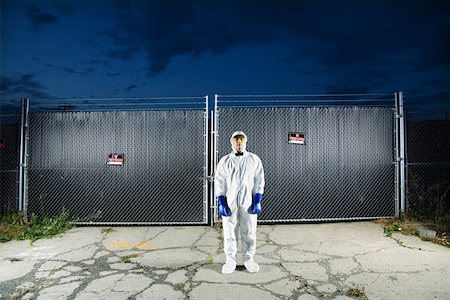 Man in biohazard suit standing outside security gate Stock Photo - Premium Royalty-Free, Code: 673-02141800