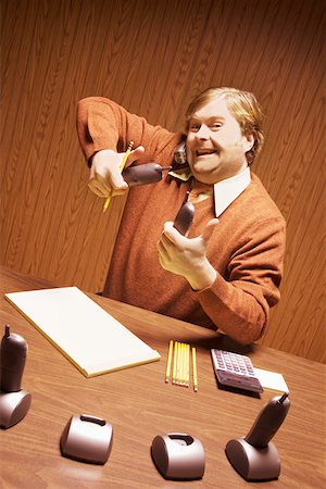 Businessman at desk using multiple telephones Stock Photo - Premium Royalty-Free, Code: 673-02142316