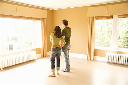 Hispanic couple looking out window in new house Stock Photo - Premium Royalty-Free, Code: 673-02143042