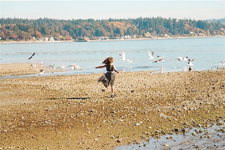 Girl running on beach in party dress Stock Photo - Premium Royalty-Free, Code: 673-02143296