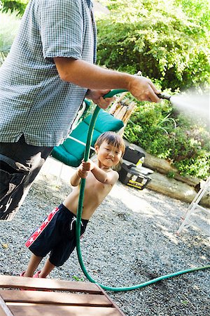 Father and son using garden hose Stock Photo - Premium Royalty-Free, Code: 673-02143328