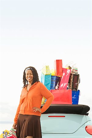 African woman next to convertible with shopping bags Stock Photo - Premium Royalty-Free, Code: 673-02143400