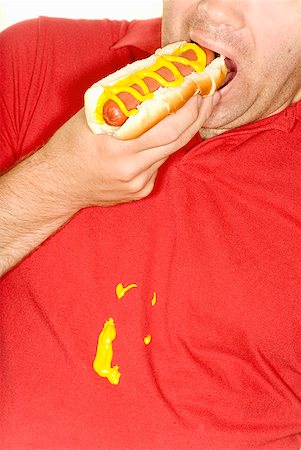 stains and discolorations - Man eating hotdog and spilling mustard on shirt Stock Photo - Premium Royalty-Free, Code: 673-02143472