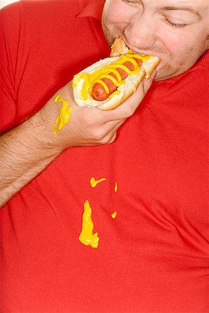 stains and discolorations - Man eating hotdog and spilling mustard on shirt Stock Photo - Premium Royalty-Free, Code: 673-02143473