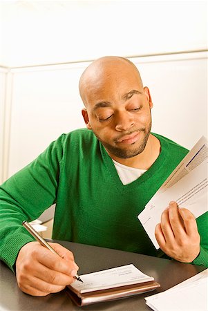 African man writing check Stock Photo - Premium Royalty-Free, Code: 673-02143904