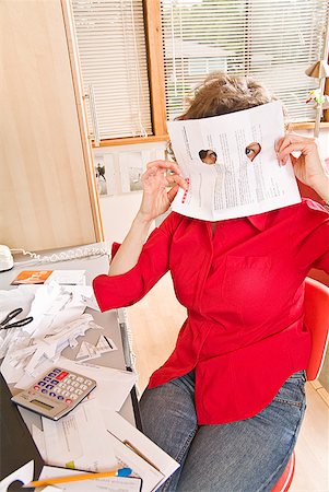 Woman looking through holes in document in home office Stock Photo - Premium Royalty-Free, Code: 673-02216274