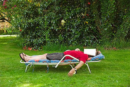 Man with magazine over face relaxing in lounge chair in backyard Stock Photo - Premium Royalty-Free, Code: 673-02216345