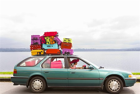 Woman and dog driving car stacked with colorful suitcases Stock Photo - Premium Royalty-Free, Code: 673-02216512